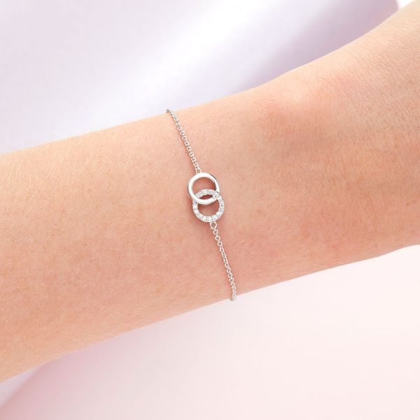 a ladies wrist wearing an olivia burton bracelet that has 2 hops interlinking with one having a row of white crystal