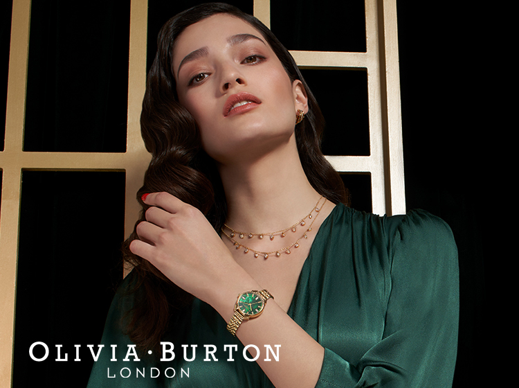 Model wearing green dress wearing Olivia Burton Art Deco green dial bracelet watch and necklace.