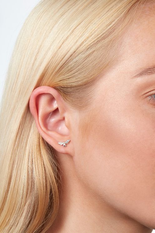 Lady with blonde hair wearing small silver bee studs on earlobe.