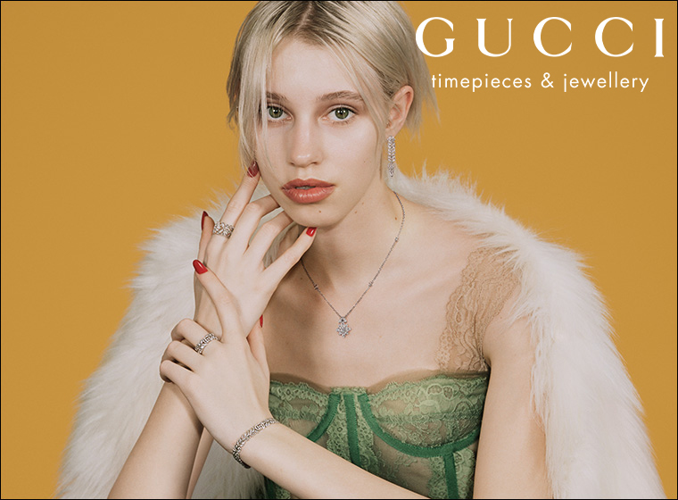 Model looking at the camera wearing Gucci jewellery.