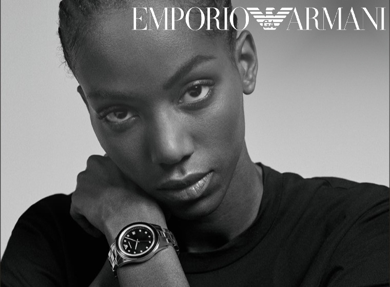 Close up image of a woman looking at the camera wearing a Emporio Armani watch.