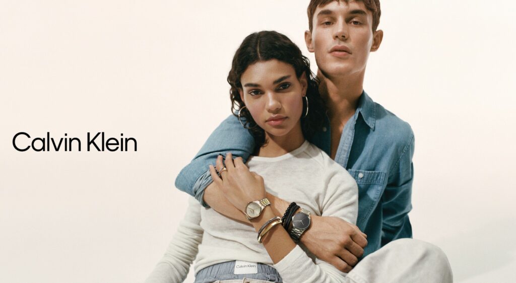 Male model in blue denim shirt with a CK watch and bracelets with are over female model